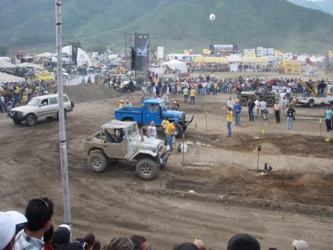1995 Ford F-150 - A crowd watches as several off-road vehicles navigate a challenging dirt course during an event.
