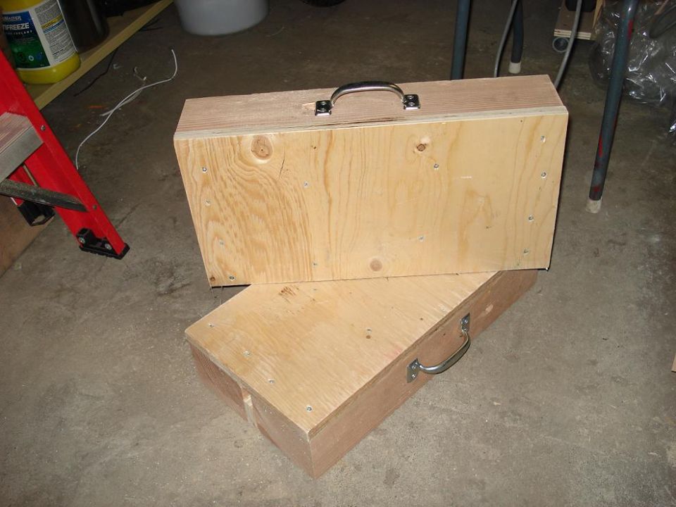 Homemade plywood wheel ramp pads with chrome handles on a garage floor
