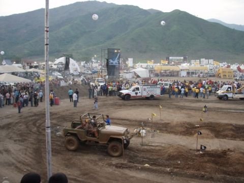 1995 Ford F-150 - An outdoor event with multiple vehicles and a large crowd gathered around a dirt track.