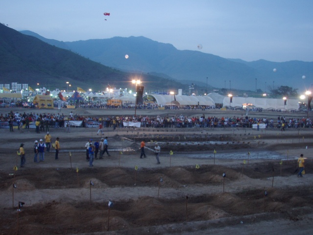 Outdoor event scene with tents, crowds, and mountains in the background