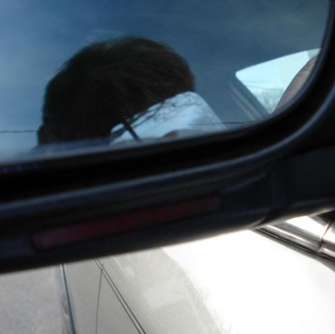 1999 Ford Crown Victoria - Reflection of a person is visible in the side window of a car, with a red reflector strip on the door frame.