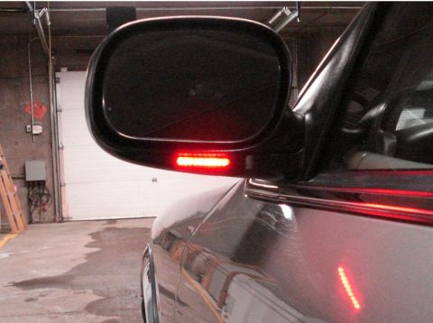 1999 Ford Crown Victoria - Close-up of a side mirror with a row of red LED turn signal lights illuminated.