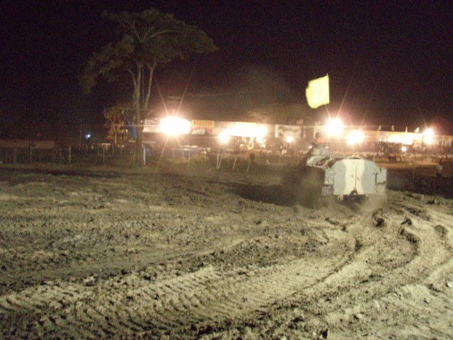 Camouflaged truck driving on a muddy track at night, kicking up dust