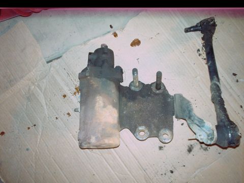 1984 Ford Bronco - A dirty steering linkage and power steering component are shown on a cardboard surface.