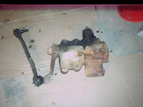 1984 Ford Bronco - A rusty steering gear box with a tie rod end attached, likely for an older vehicle.