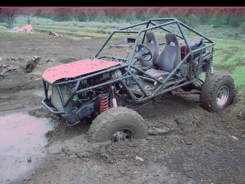 1984 Ford Bronco - This custom off-road vehicle is deeply embedded in thick mud, with its front tire submerged.