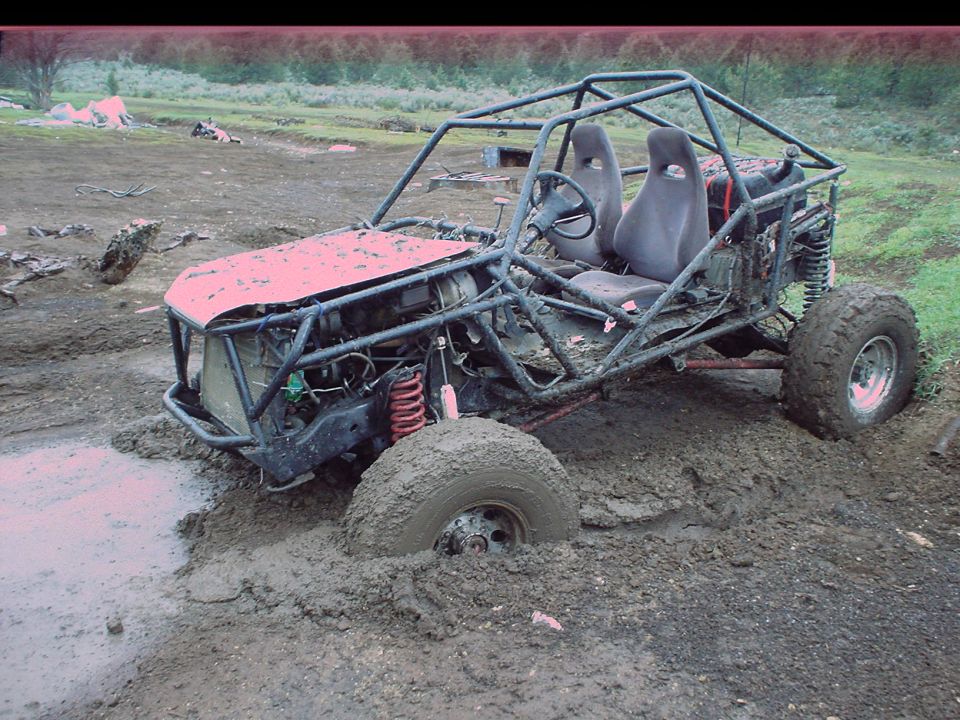Buggy with roll cage stuck in mud, front wheel deep in muck