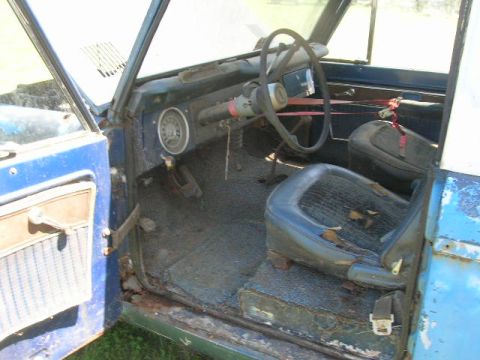 1992 Ford Mustang - The interior of a classic Ford Bronco shows signs of wear and tear, with faded upholstery and rust on the door frame.