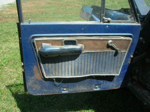 1992 Ford Mustang - The interior of a blue vehicle door shows plaid fabric and a worn armrest, suggesting a 1974 model year.