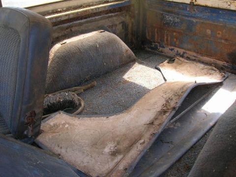 1992 Ford Mustang - Interior view of a worn and rusty truck bed, with a torn seat and debris on the floor.