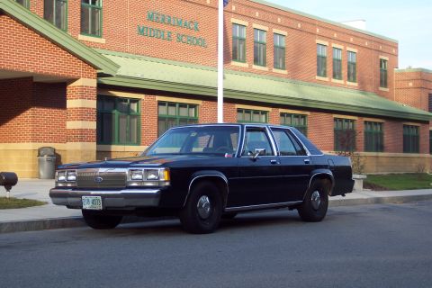 2001 Ford Crown Victoria - A dark 2001 Ford Crown Victoria is parked on the street in front of Merrimack Middle School.