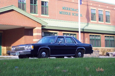 2001 Ford Crown Victoria - A dark sedan is parked in front of Merrimack Middle School.