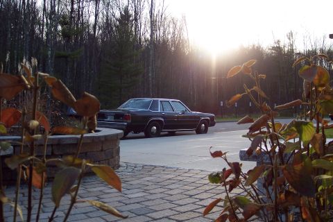 2001 Ford Crown Victoria - A dark 2001 Ford Crown Victoria is parked in a lot, viewed from the rear as the sun sets.