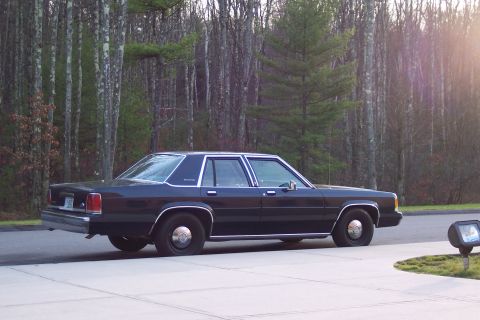 2001 Ford Crown Victoria - Side view of a dark blue 2001 Ford Crown Victoria parked outdoors near a wooded area.