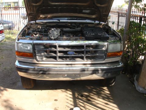 1992 Ford F-350 - The front grille and headlights of a 1992 Ford F-350 are visible, with the hood open to reveal the engine compartment.