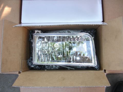 1992 Ford F-350 - Headlight assembly packaged in a cardboard box, ready for shipping or installation.