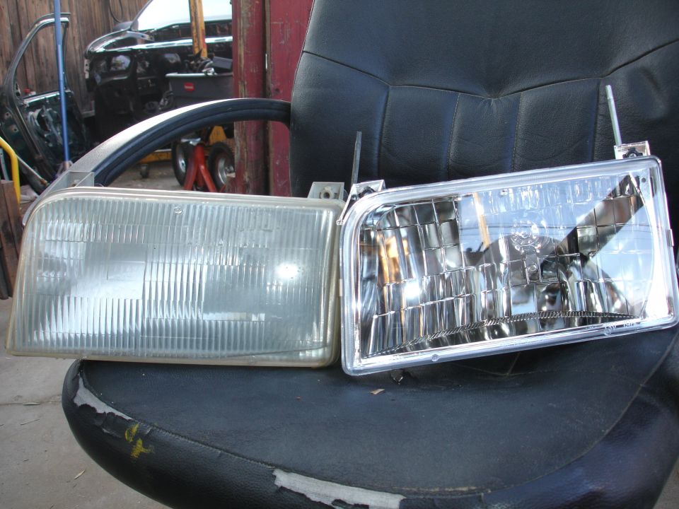 Old headlight next to a new one on a chair. Another car is in the background