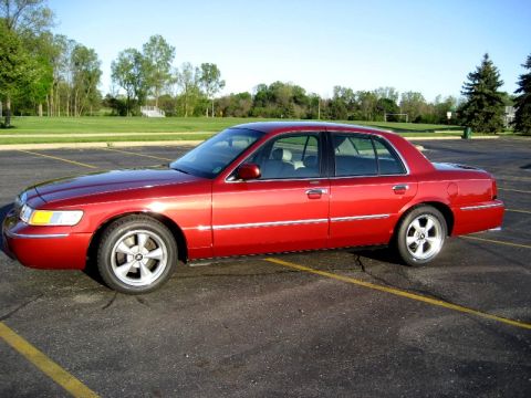 2000 Mercury Grand Marquis - A red 2000 Mercury Grand Marquis sedan is parked in a lot on a sunny day.