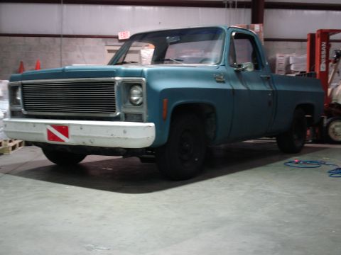 1979 Chevrolet C/K Pickup - A blue pickup truck with a white bumper is parked inside a warehouse.