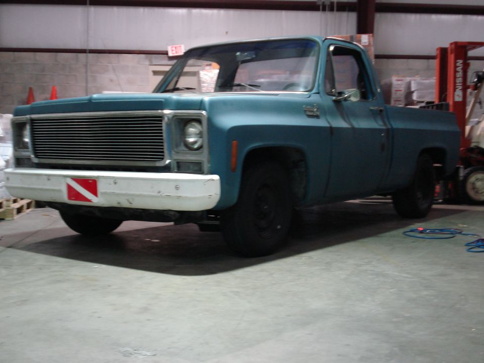 Blue pickup truck with white bumper and dive flag sticker, parked indoors