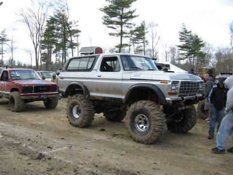1977 Ford Bronco - A lifted 1978 Ford Bronco with large off-road tires is parked next to a red GMC pickup truck.