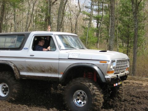 1977 Ford Bronco - This lifted Ford Bronco is navigating a muddy trail in a wooded area.