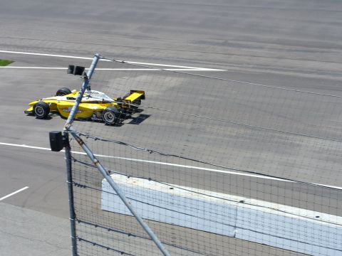 1991 Ford Probe - A yellow and white race car drives on a track, seen from above and behind a fence.