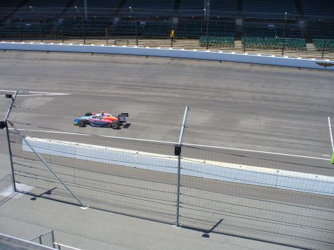 1991 Ford Probe - An open-wheel race car speeds along a paved track, with grandstands visible in the background.