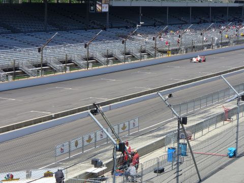 1991 Ford Probe - An IndyCar races on a track with empty grandstands in the background. The image includes a watermark for SuperMotors.net.