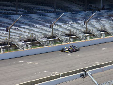 1991 Ford Probe - A race car speeds around a track with empty grandstands in the background.