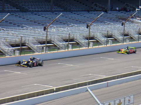 1991 Ford Probe - Two race cars are on the track at a speedway with empty bleachers visible.