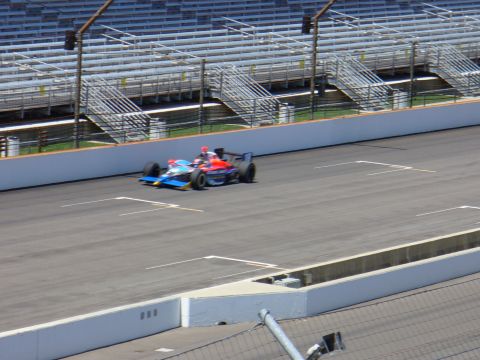1991 Ford Probe - An IndyCar racing car speeds around a track with grandstands in the background.