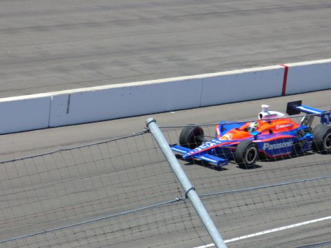 1991 Ford Probe - A race car with blue and orange paint zooms around a track, displaying 'Panasonic' branding.