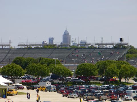 1991 Ford Probe - A large parking lot is filled with vehicles, with a stadium and city skyline visible in the distance.