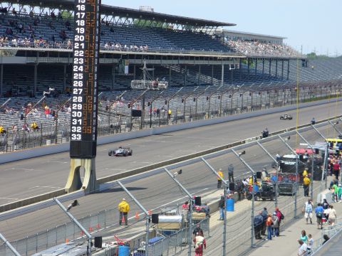 1991 Ford Probe - Race cars compete on a track with spectators in the grandstands and a large scoreboard displaying lap times.