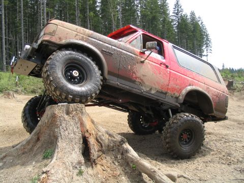 1989 Ford Bronco - Red Ford Bronco navigating an obstacle course on a dirt trail.