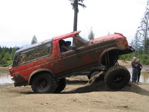 1989 Ford Bronco - This heavily modified SUV is shown off-roading in the mud. The year is estimated based on body style.