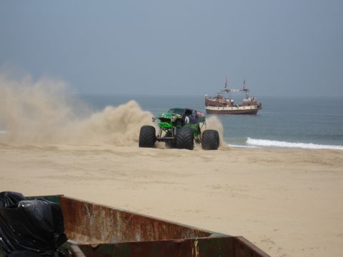 1996 Ford Bronco - A monster truck drives on the sand near the ocean, while a pirate ship sails in the background.