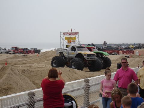 1996 Ford Bronco - Monster trucks are lined up on a beach, with a large Toyota sign visible behind them.