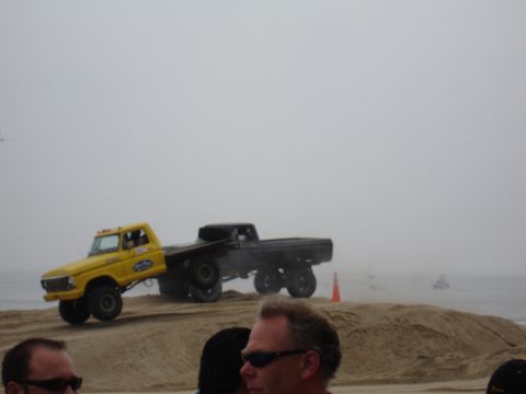 1996 Ford Bronco - Two trucks are on a sandy incline near the ocean on a hazy day.