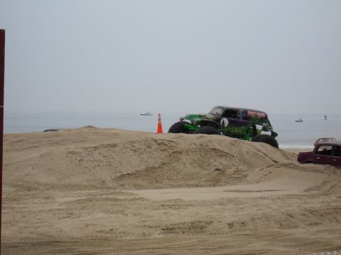 1996 Ford Bronco - A monster truck sits atop a sand dune with the ocean in the distance.