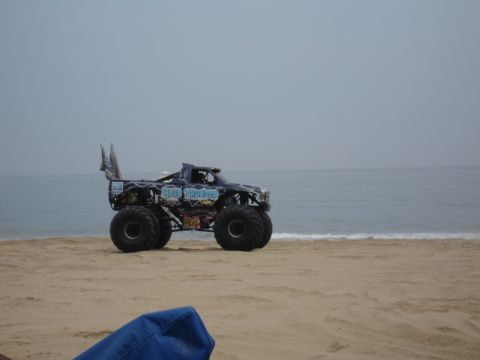 1996 Ford Bronco - A monster truck named 'Blue Thunder' is parked on the sand near the ocean waves.