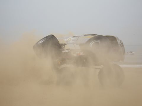 1996 Ford Bronco - Monster truck event on the beach, kicking up a large cloud of sand.