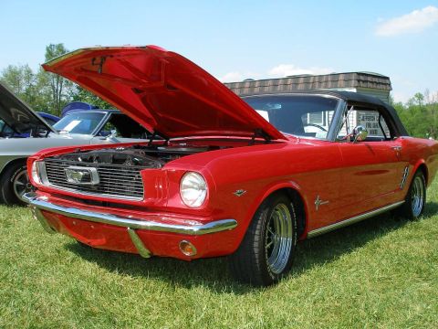 1998 Ford Crown Victoria - A classic red convertible is displayed with its hood open at an outdoor car show.