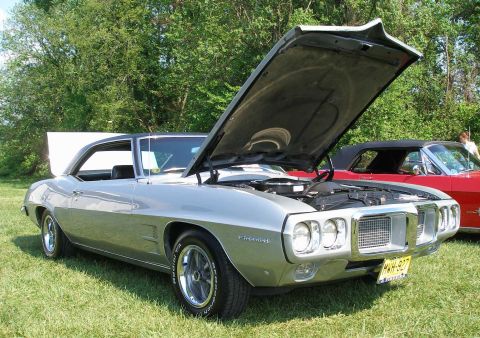 1998 Ford Crown Victoria - A silver 1969 Pontiac Firebird is displayed with its hood open at an outdoor car show.