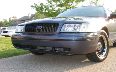 1998 Ford Crown Victoria - A dark gray Ford Crown Victoria is shown from the front, with another white vehicle visible in the background.