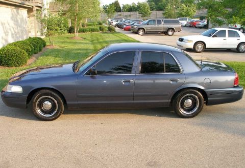1998 Ford Crown Victoria - A dark blue Ford Crown Victoria is parked in a lot with other vehicles visible.