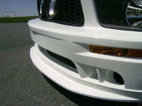 2007 Ford Mustang - Close-up of a white Ford Mustang's front bumper and grille, showing the distinctive headlights and turn signals.