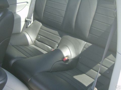 2007 Ford Mustang - The interior of a car shows black leather rear seats with visible seatbelt buckles.