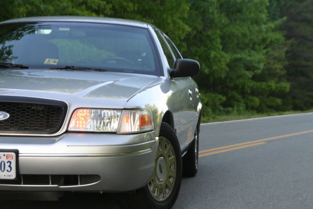Silver 2004 Ford Crown Victoria with a license plate reading '03' parked on the side of a road